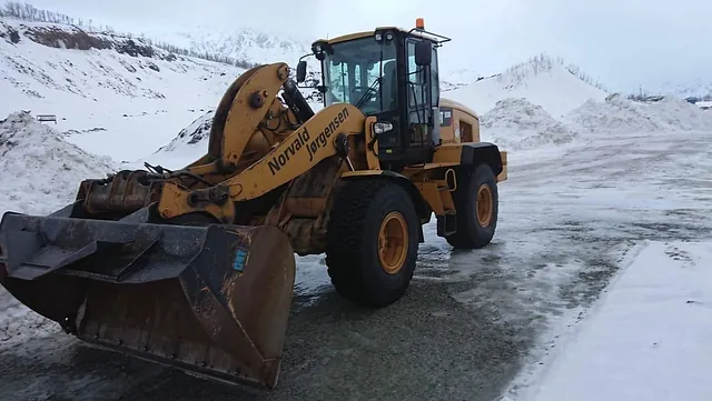 Hjullaster står parkert på islagt underlag i snødekt steinbrudd eller anleggsområde.