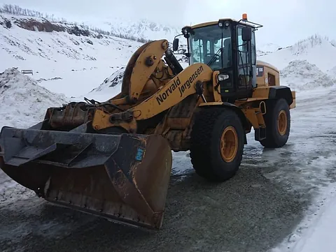 Hjullaster står parkert på islagt underlag i snødekt steinbrudd eller anleggsområde.